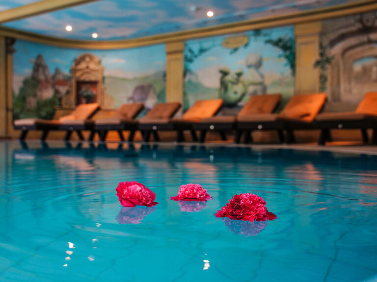 Blumen schwimmen im hellen Blau des Pools im Sponsel-Regus Hotel in Franken.