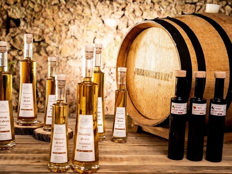 Eine Gruppe Flaschen mit Schnaps steht neben einem Holzfass