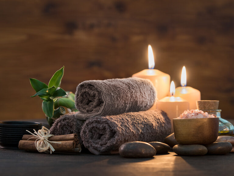 Sanftes Kerzenlicht und weiche Handtücher schaffen ein Gefühl von Wellness.