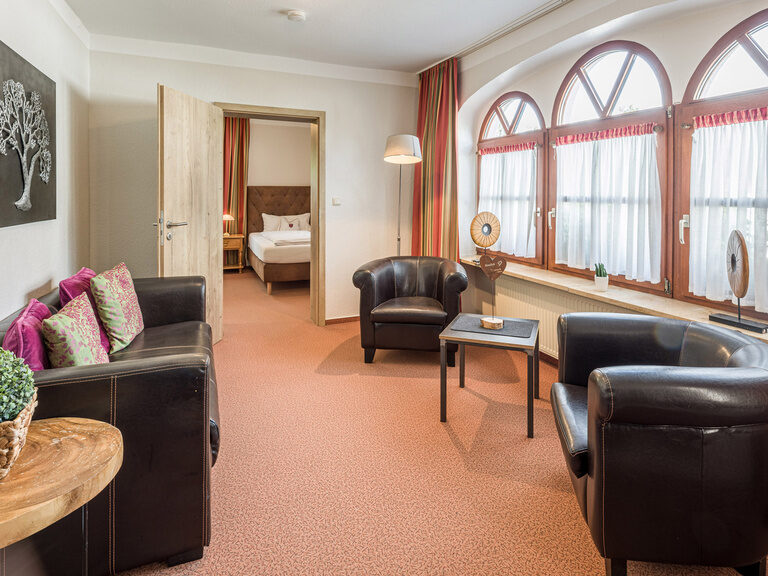 Ein gemütlicher Wohnbereich im Familienzimmer im Gästehaus, ausgestattet mit einer bequemen Sitzgruppe und einem Couchtisch.