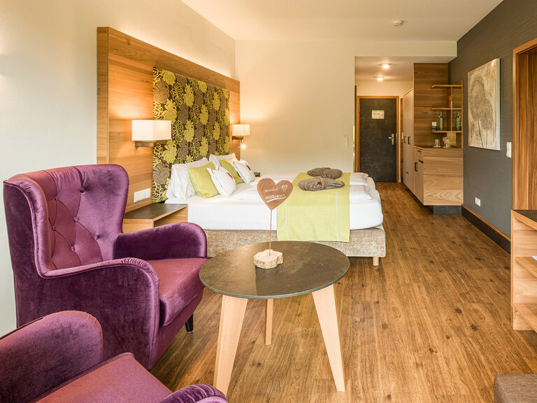 Komfortable Holzmöbel und Sessel im Wohnzimmer der Landhaus Suite Sonneck